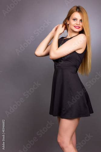 Portrait of happy young blonde woman wearing a mini black dress