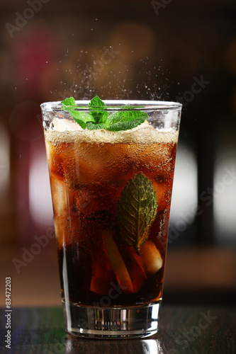 Glass of cocktail in bar on bright blurred background