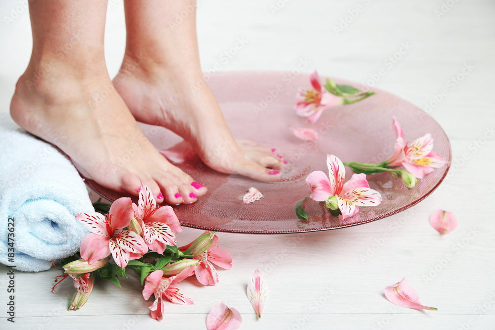 Woman washing beautiful legs in bowl, on light background. Spa procedure concept Woman washing beautiful legs in bowl, on light background. Spa procedure concept