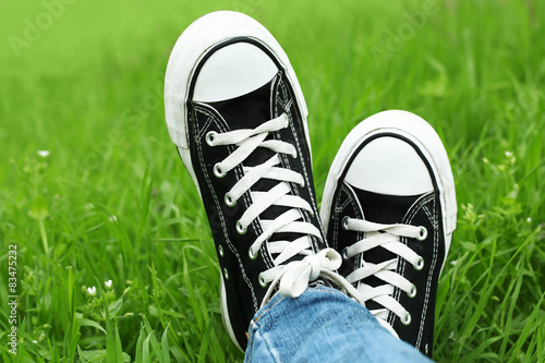 Female feet in gumshoes on green grass background