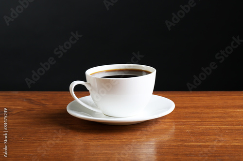 Cup of coffee on table on dark background