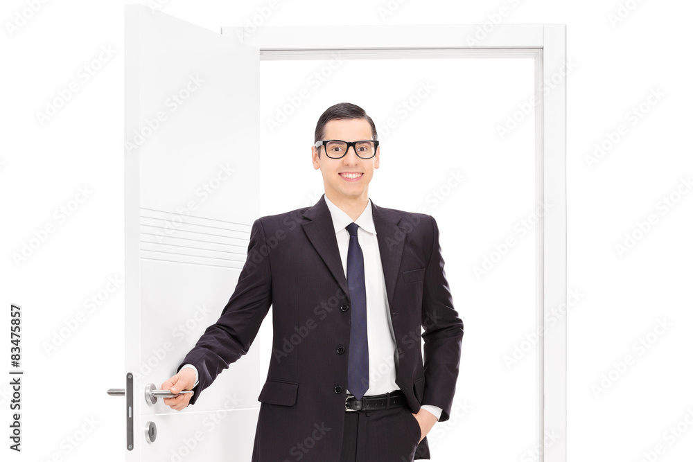 Young businessman in a black suit posing in front of an opened d Young businessman in a black suit posing in front of an opened d