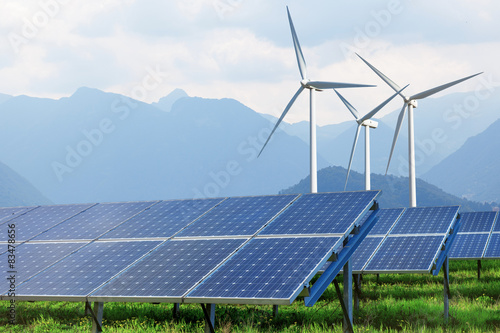 solar panels and wind turbines against mountains