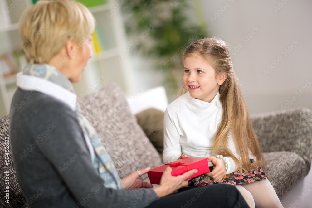 Cute girl giving her grandmother a gift