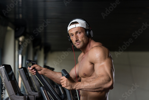 Mature Man Doing Aerobics Elliptical Walker In Gym