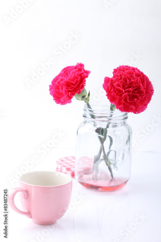 pink ceramic cup and red carnation flower