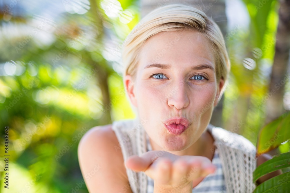 Fototapeta premium Pretty blonde woman smiling at the camera and blowing kiss