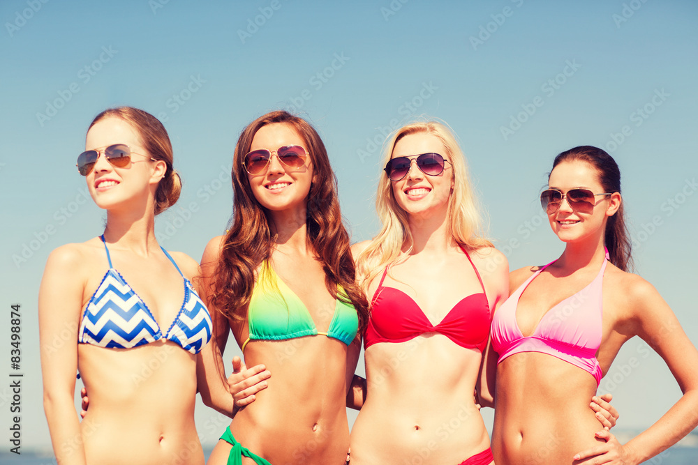 group of smiling young women on beach