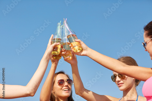 close up of happy young women clinking bottles