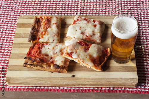 Tranci di pizza margherita e birra su tagliere di legno