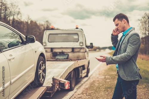 Tableau sur toile Man calling while tow truck picking up his broken car