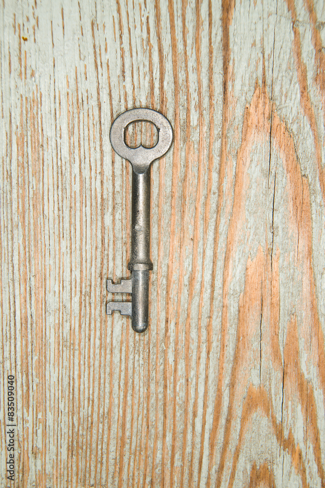 Old key from the lock on a wooden texture Old key from the lock on a wooden texture