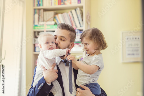 Young businessman with his daughters in his arms