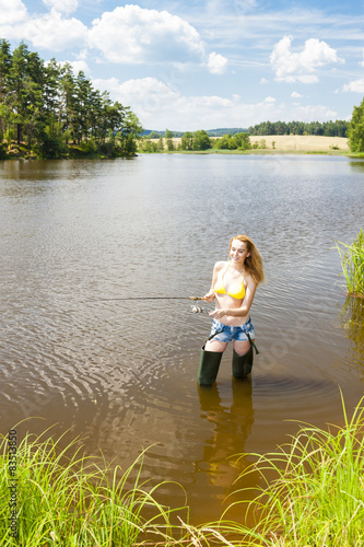young woman fishing in pond during summer