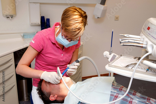 Obraz na plátně portrait of a young female dental hygienist cleaning the teeth