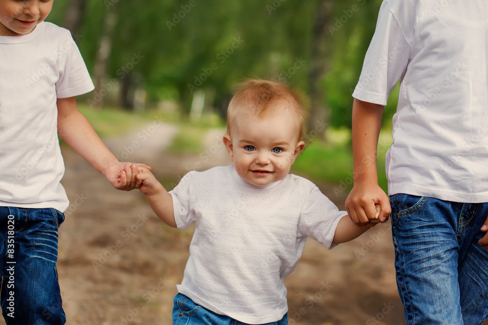 Fototapeta premium children lead on a footpath by the hand the younger brother in p