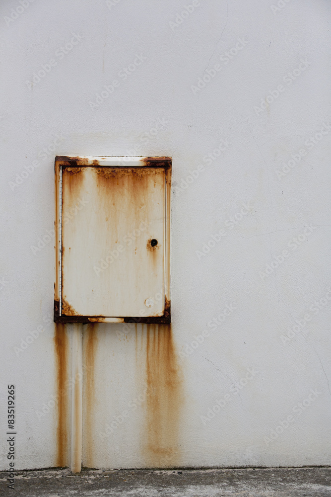 A wall mounted metal box with rust stains down the wall. A wall mounted metal box with rust stains down the wall.