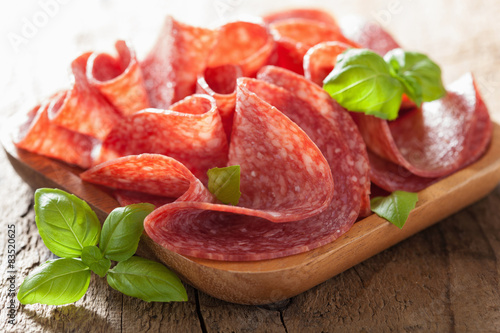 Obraz na płótnie salami slices in wooden plate w salonie