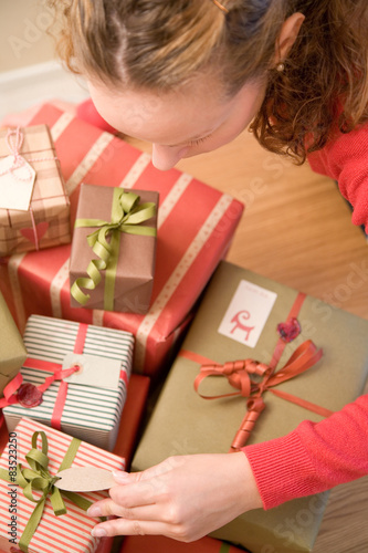 Overhead view of a woman looking at tags on a stack of Christmas gifts photo