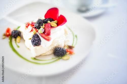 Merangue topped with cream and fresh fruit photo