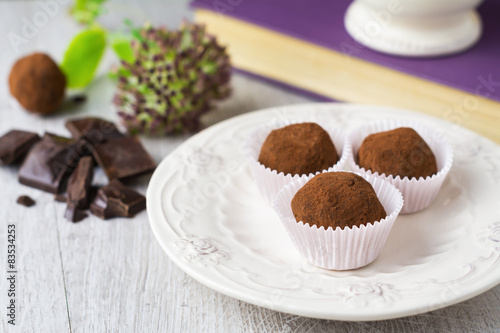 Close-up of Three cocoa covered chocolate truffles on a plate with pieces of chocolate photo