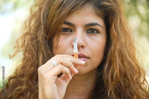 Portrait of beautiful woman with long hair smoking a cigarette photo