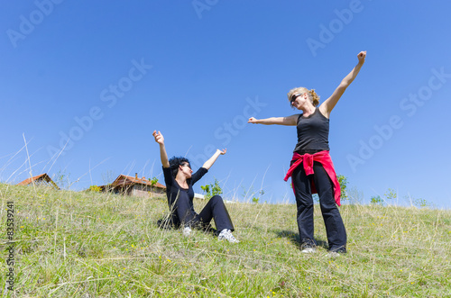two pretty young women hands up on top of hill