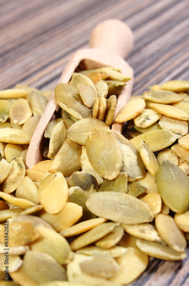 Pumpkin seeds with spoon on wooden background Pumpkin seeds with spoon on wooden background