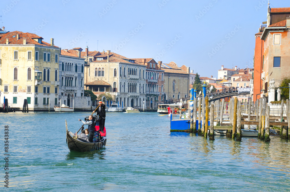 Gondola with tourists sailing on a typical Venetian water 