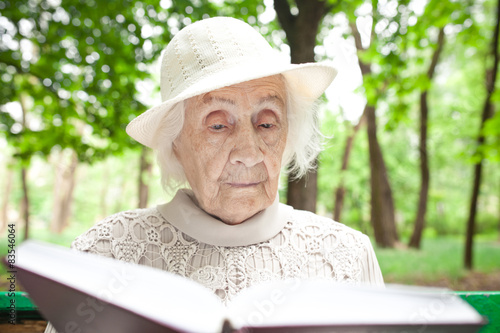portrait of  happy grandmother on a park bench, read book