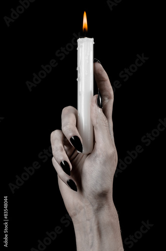 hands holding a candle, a candle is lit, black background