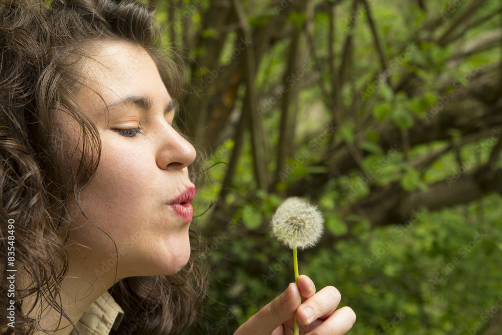 Young woman blowing a flower