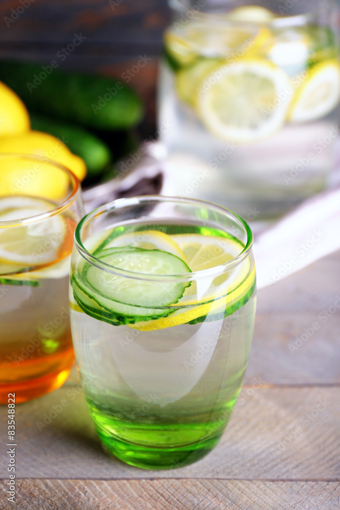 Fresh water with lemon and cucumber in glassware on wooden table, closeup Fresh water with lemon and cucumber in glassware on wooden table, closeup