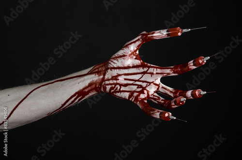 Bloody hand with syringe on the fingers, toes syringes in studio