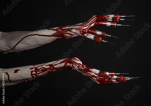 Bloody hand with syringe on the fingers, toes syringes in studio