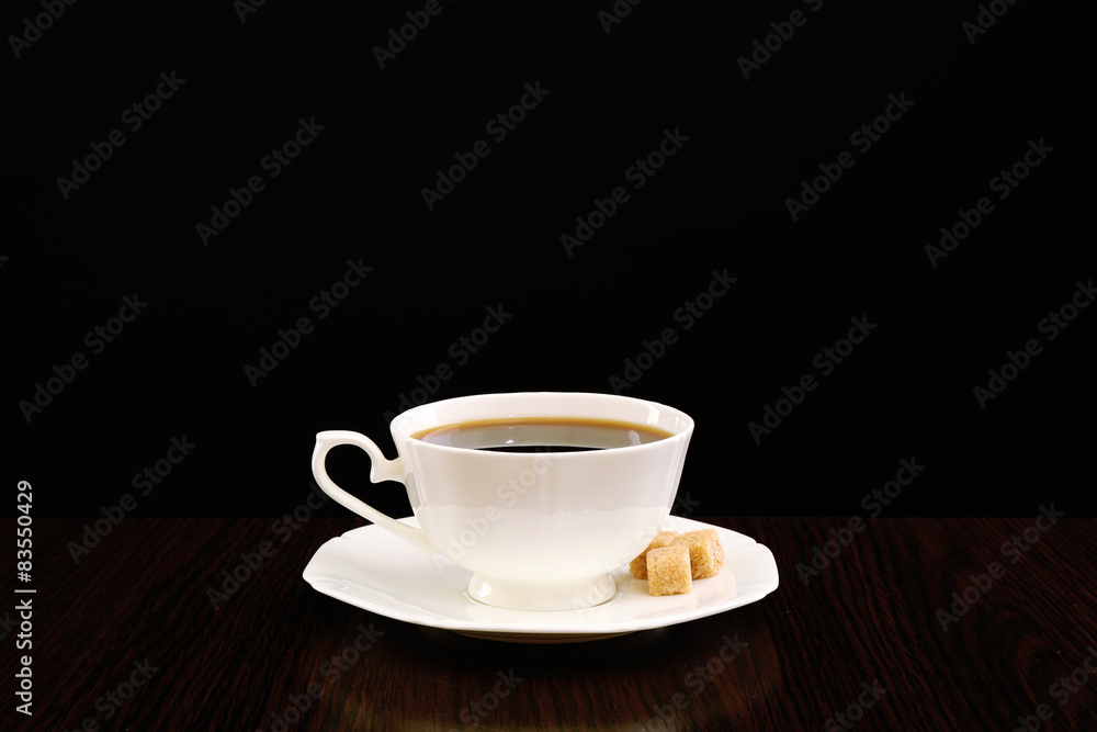 Fototapeta premium Cup of coffee with lump sugar on wooden table, on dark background