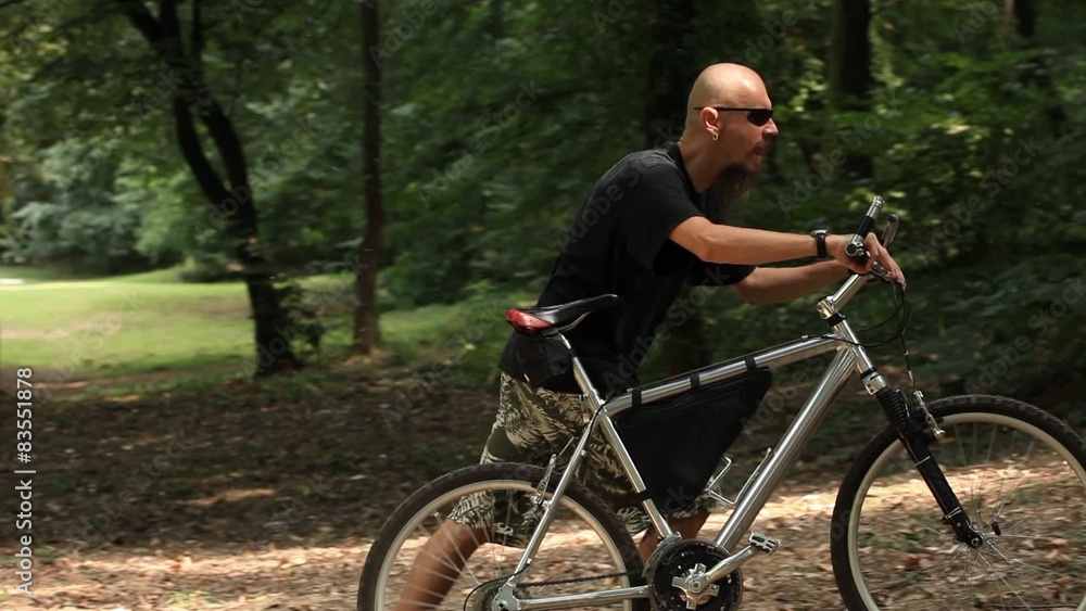 Mid adult man riding mountain bicycle in forest Mid adult man riding mountain bicycle in forest