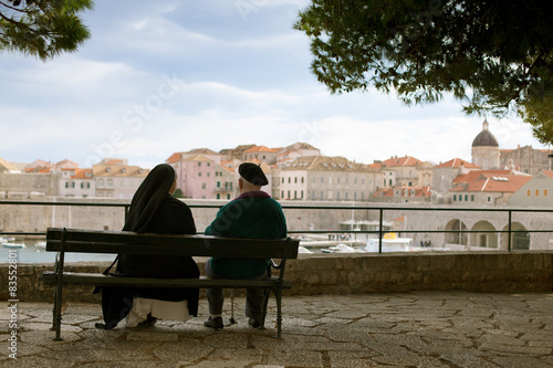elderly couple sitting on bench watching Dubrovnik panorama