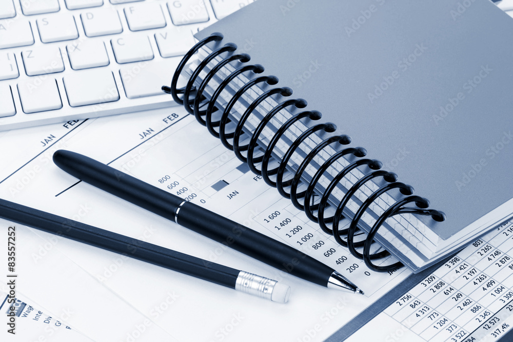 Office desk with reports, blank notepad and supplies Office desk with reports, blank notepad and supplies