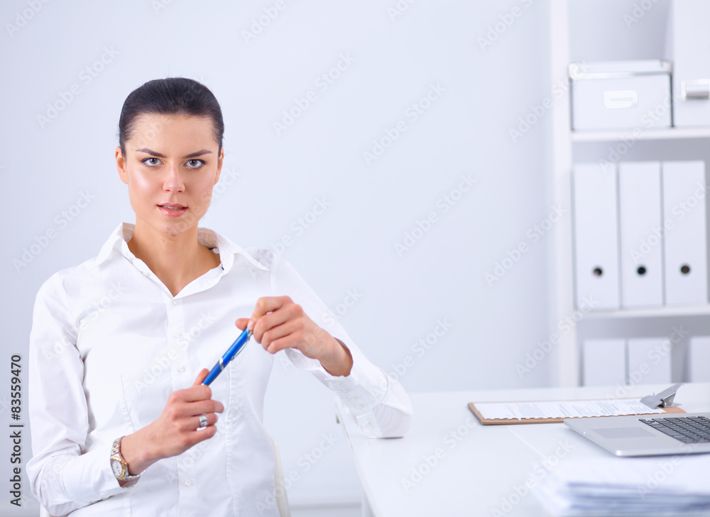 Attractive businesswoman sitting on a desk with laptop in the Attractive businesswoman sitting on a desk with laptop in the