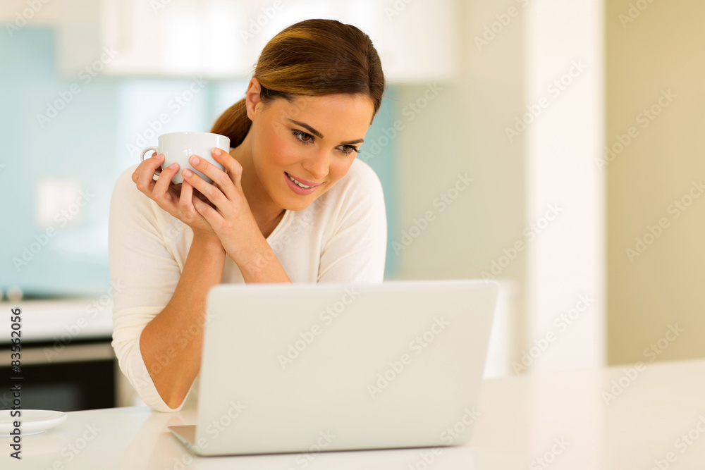 young woman drinking coffee while using laptop young woman drinking coffee while using laptop