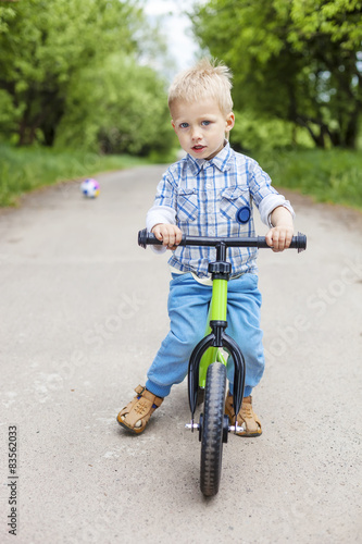 Fototapeta Naklejka Na Ścianę i Meble -  Little boy riding learner bike in park
