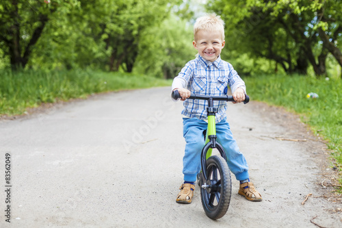 Fototapeta Naklejka Na Ścianę i Meble -  Happy little boy riding learner bike in park 