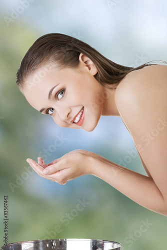 Smiling woman washing her face.