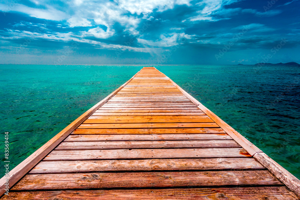 Fototapeta premium Empty Wooden Dock Over Vibrant Tropical Blue Water