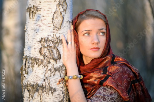 Russian girl in a scarf in a birch forest close up 