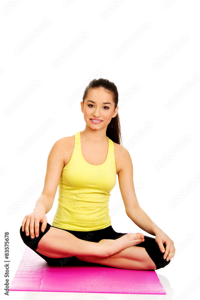 Fitness woman sitting on exercise mat.