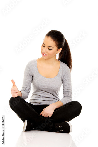 Woman sitting cross legged with thumbs up.