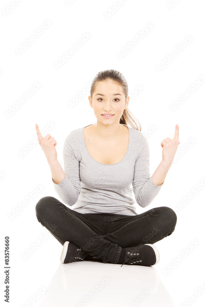 Woman sitting cross legged pointing up. Woman sitting cross legged pointing up.