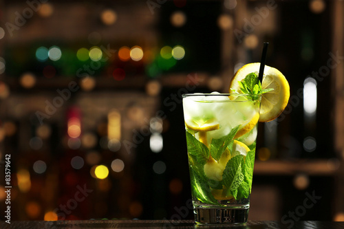 Glass of cocktail in bar on bright blurred background